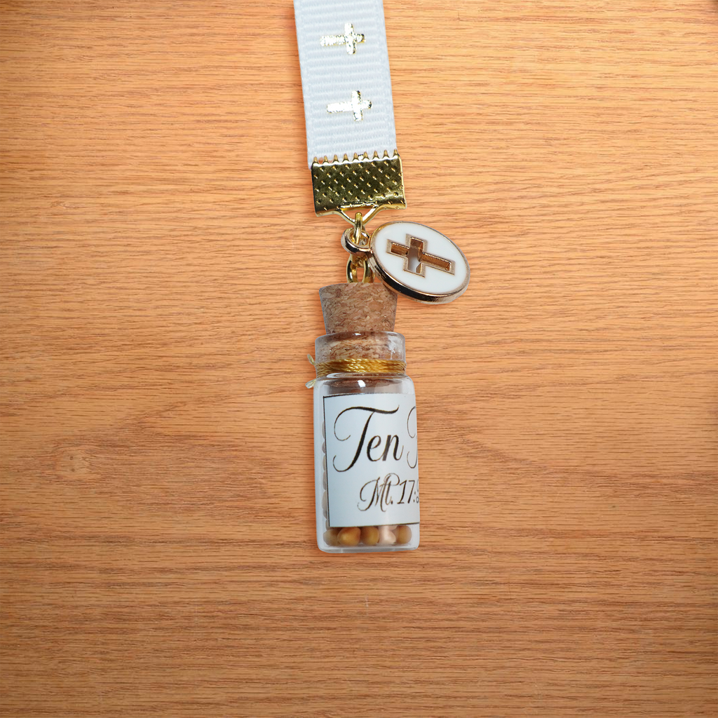 Separador de liston blanco con cruces doradas, borla, coldije y frasco con semillas de mostaza